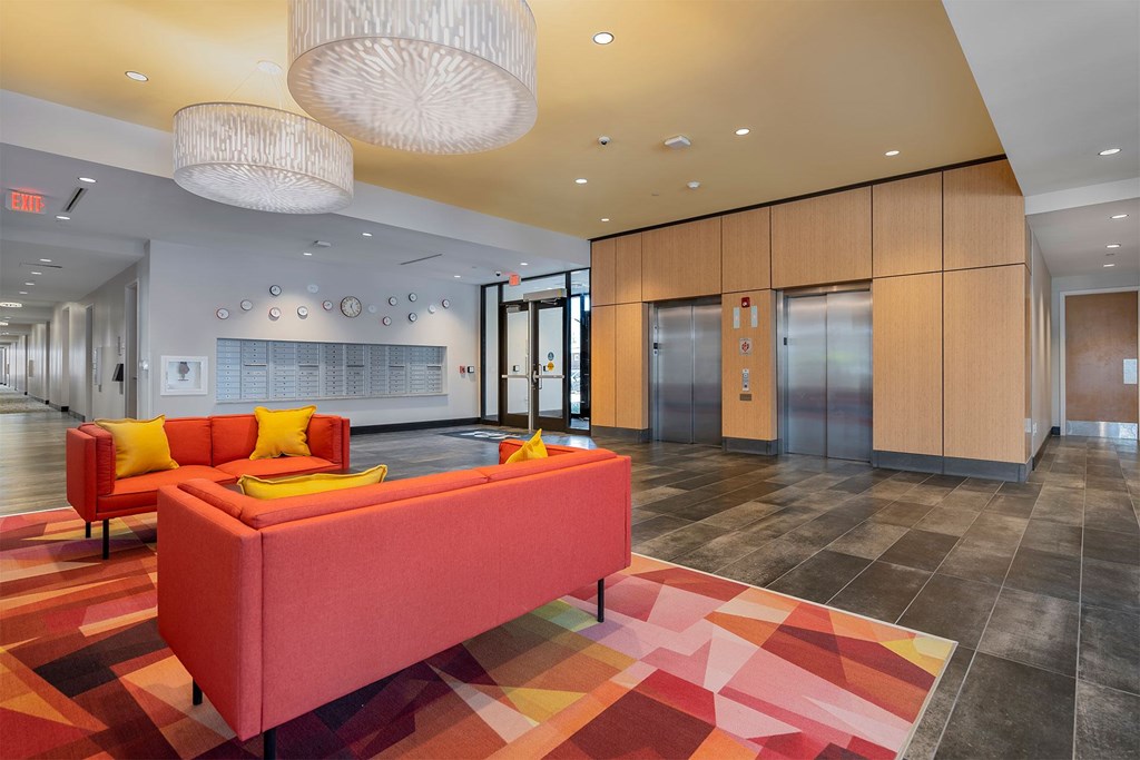 A red sofa with yellow pillows in a modern hallway.