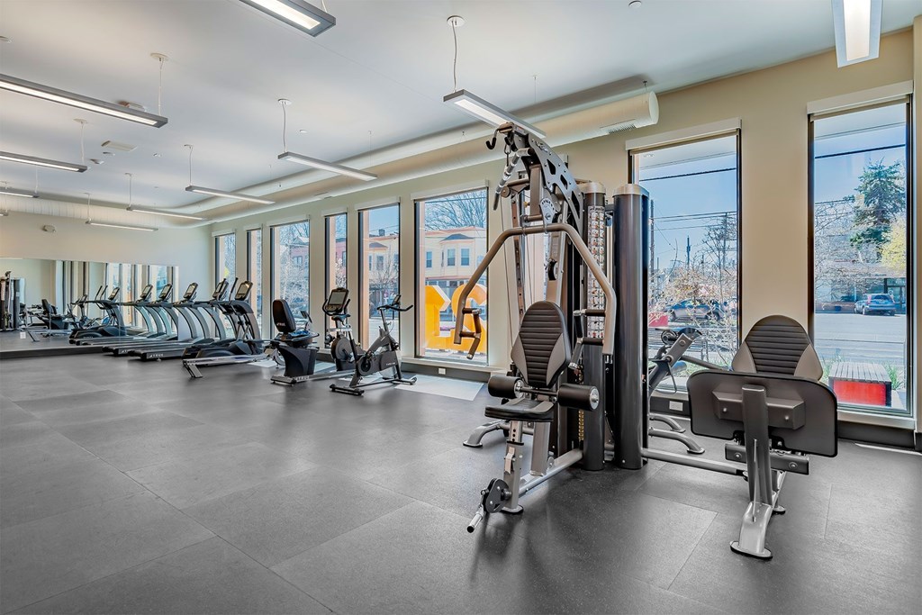 A gym with a variety of equipment including treadmills, weights, and exercise machines.