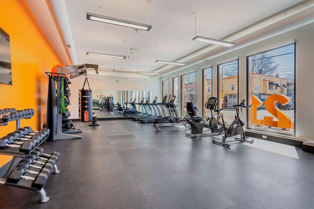 A gym with a variety of equipment including treadmills, weights, and exercise bikes.