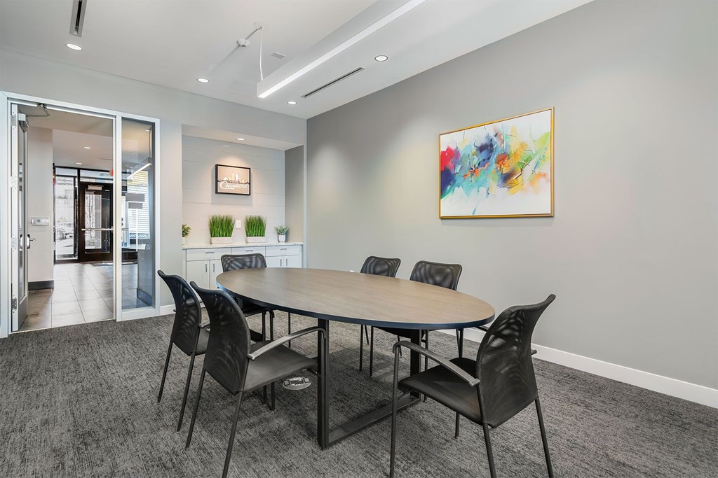 A conference room with a table and chairs and a painting on the wall.