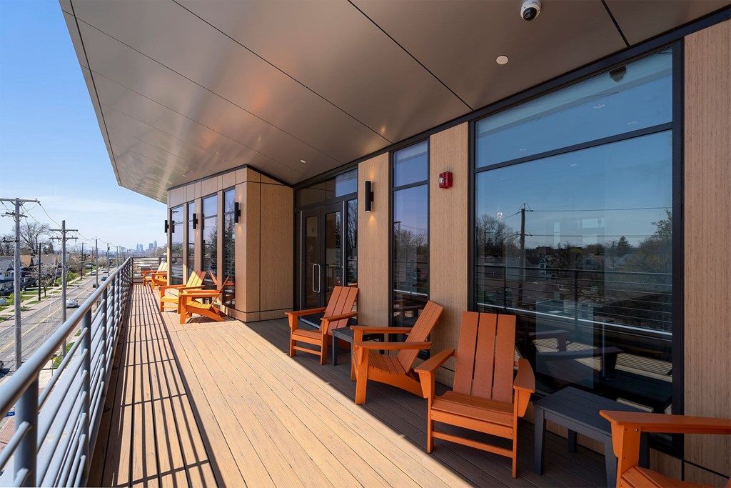 A balcony with wooden chairs and a railing.
