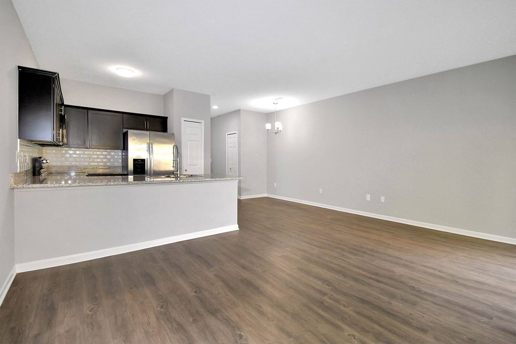 the living room and kitchen of an apartment with wood flooring
