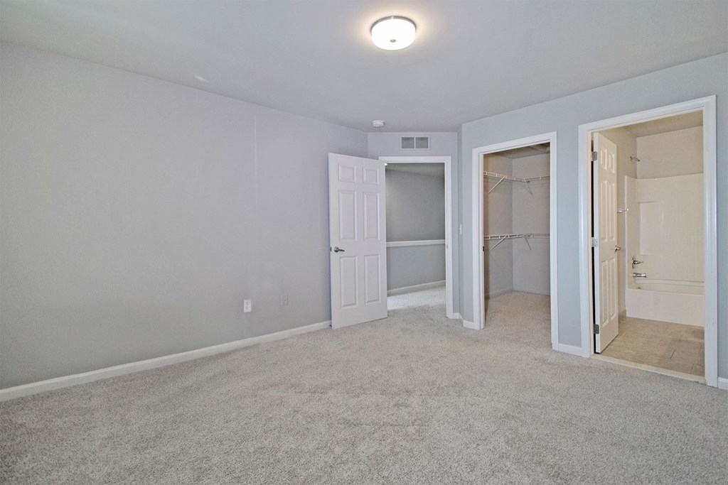 an empty bedroom with a closet and a door to a bathroom