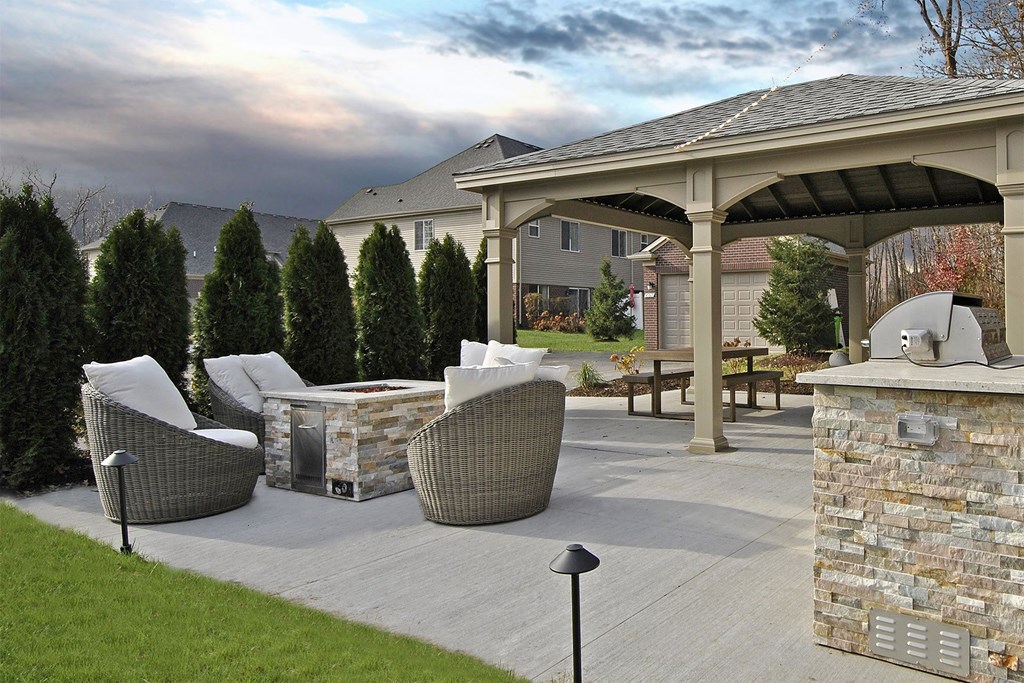 a patio with a fire pit and chairs and a pavilion