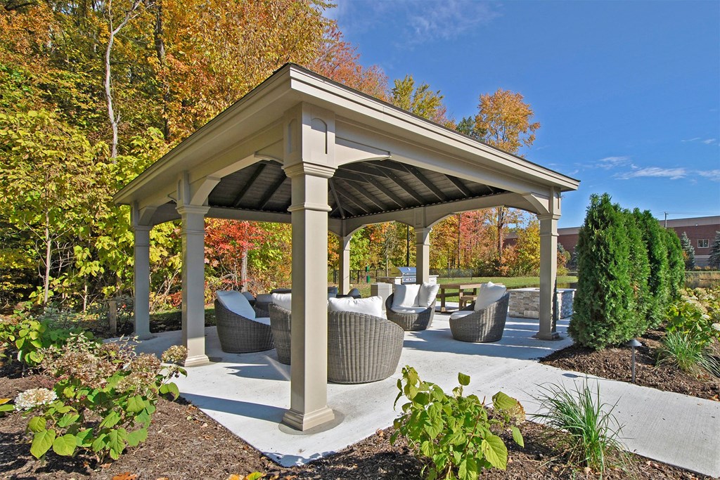 a pavilion with couches and chairs in a garden