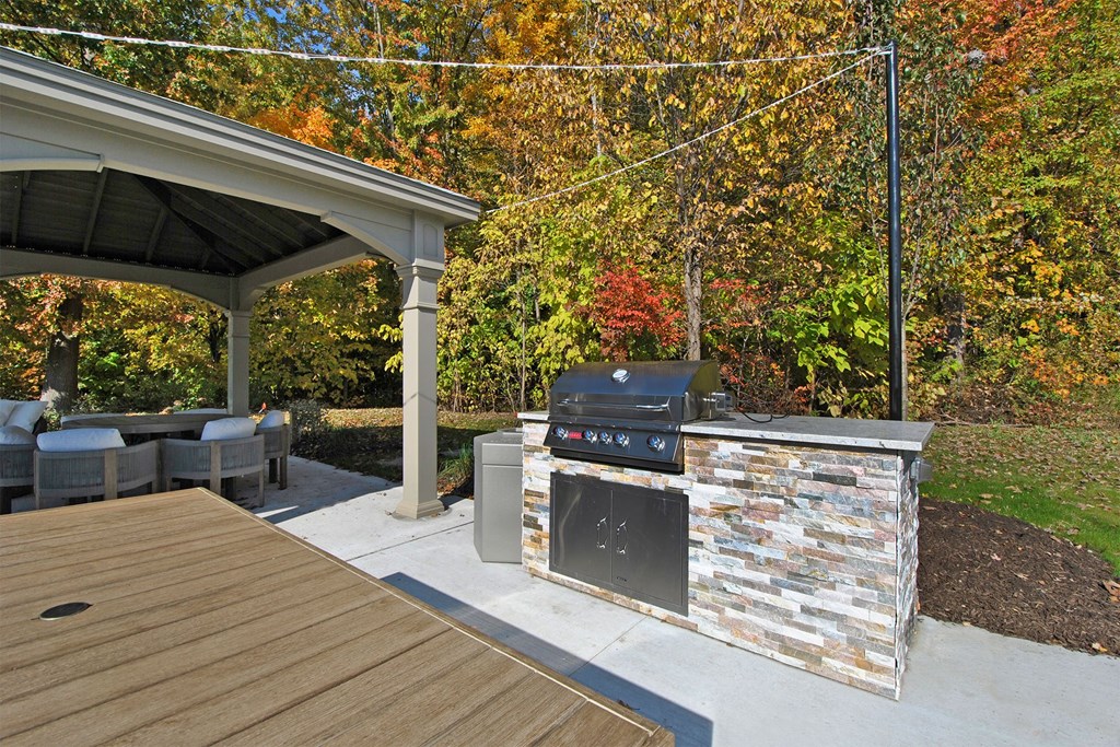 a backyard with a barbecue grill and a deck with chairs