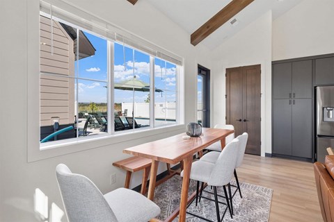 A dining room with a table and chairs in front of a window.