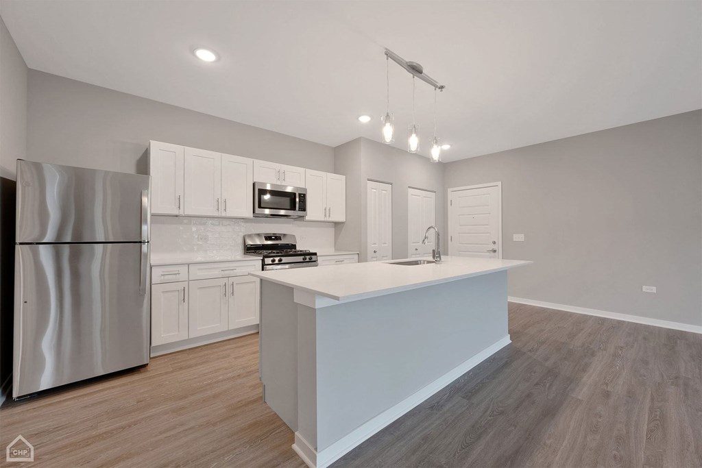 a kitchen with an island and a stainless steel refrigerator