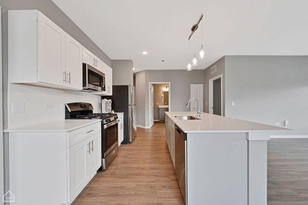 a large kitchen with white cabinets and a wooden floor