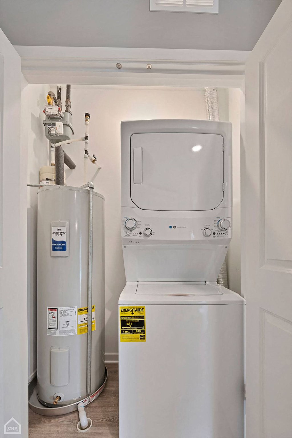 a white washer and dryer in a small room next to a water heater