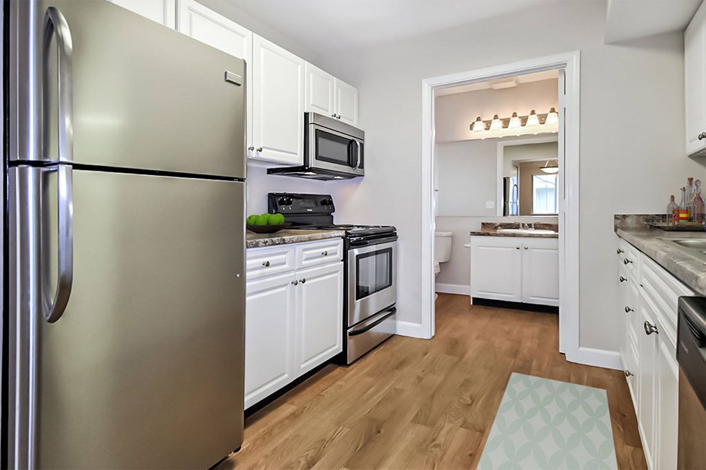 A modern kitchen with a stainless steel refrigerator and white cabinets.