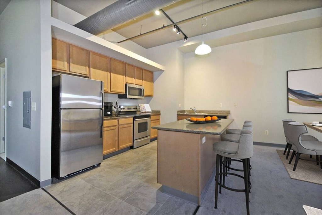 a kitchen with stainless steel appliances and a bar with chairs