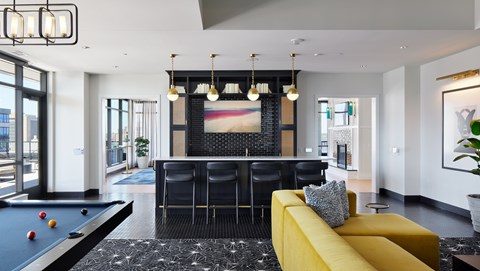 A pool table is in the middle of a room with a yellow couch.