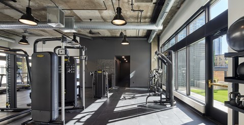 A gym with a variety of equipment including treadmills, weights, and exercise machines.