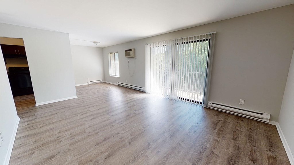 the living room and dining room of an empty house with wood flooring