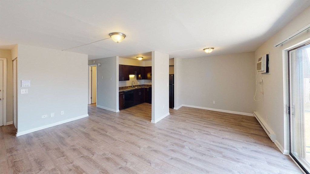 the living room and kitchen of an empty house with wood flooring