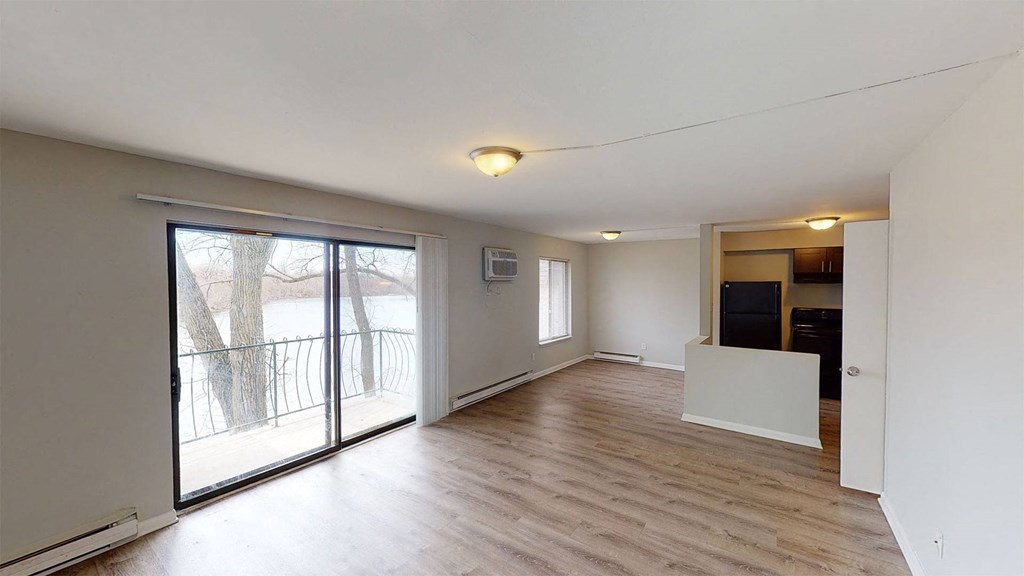 an empty living room with a sliding glass door to a balcony