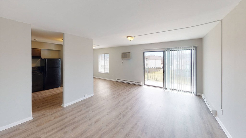 an empty living room with a sliding glass door to a balcony