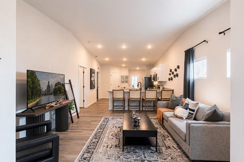 A living room with a grey couch, a black coffee table, and a large flat screen TV.