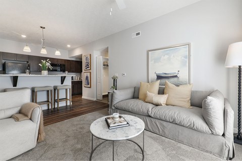 A living room with a grey couch, a white coffee table, and a painting of a boat on the wall.