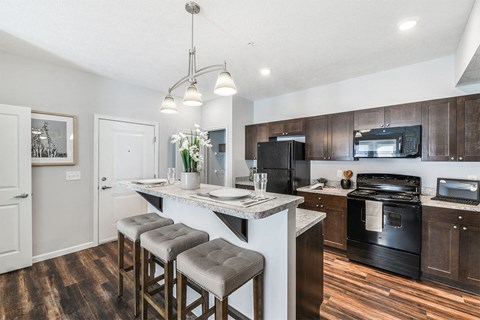 A kitchen with a white island and black appliances.