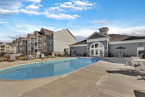 A swimming pool in front of a building with a white exterior.