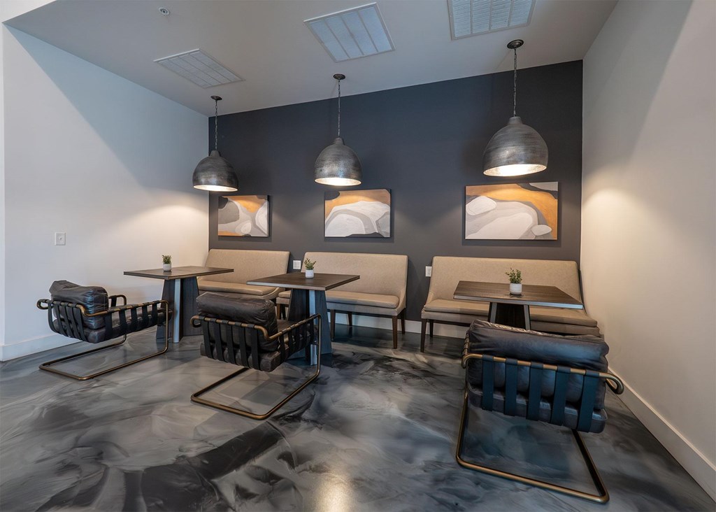 A room with black chairs and tables with a grey floor.