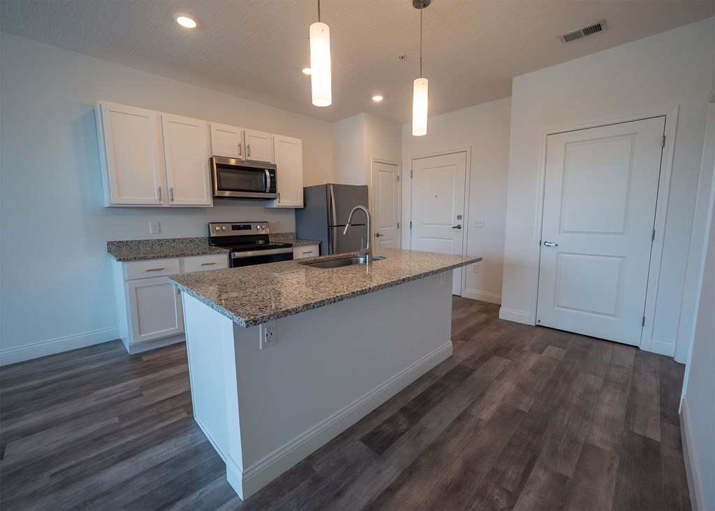 A kitchen with a granite countertop and white cabinets.