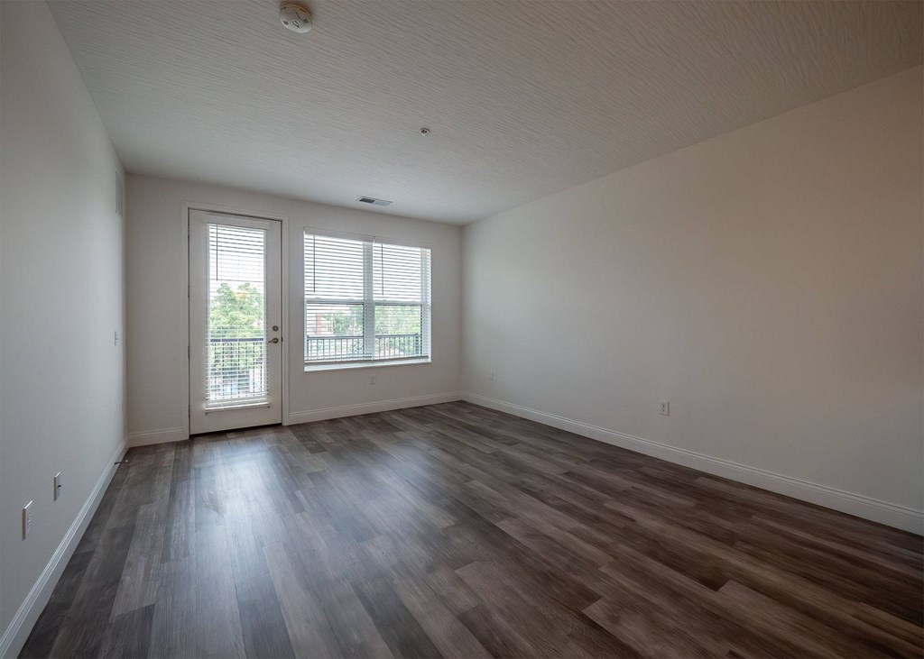A room with a sliding glass door and wood flooring.