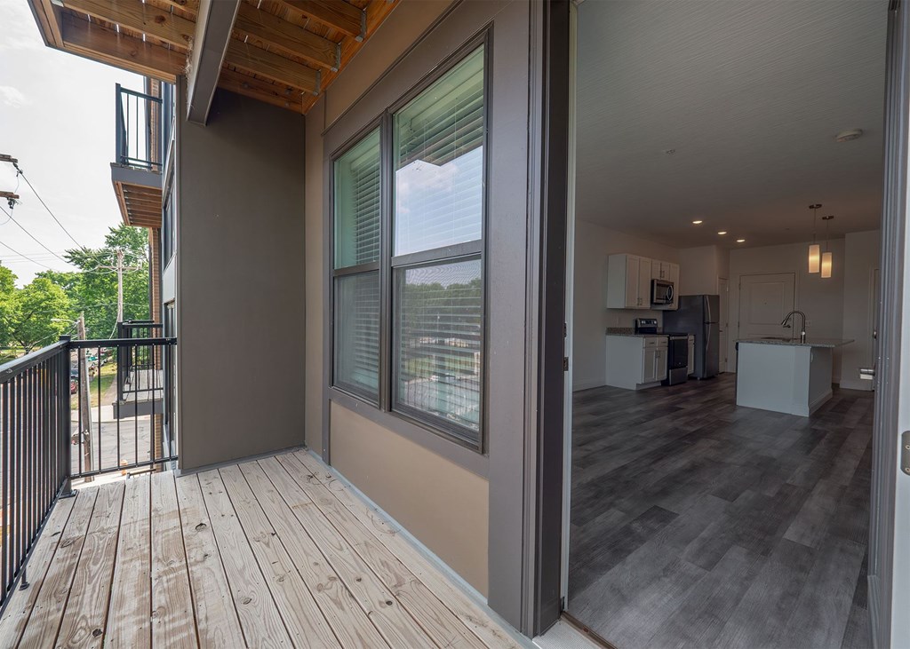 A balcony with a view of trees and a house.