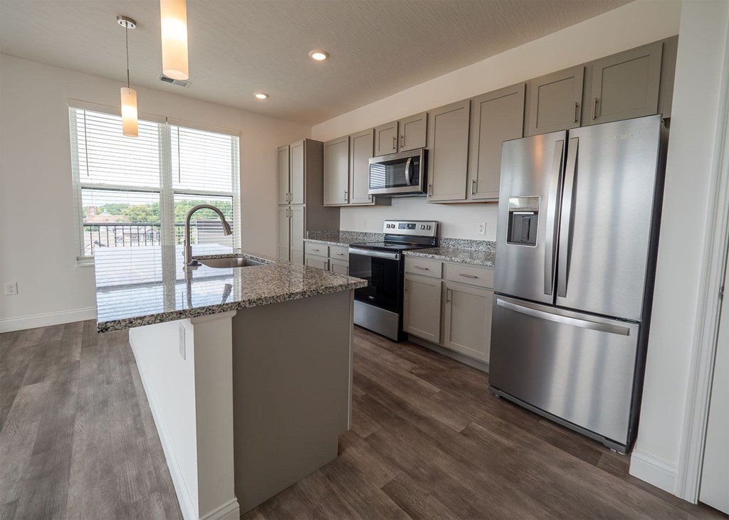 A modern kitchen with stainless steel appliances and a marble countertop.