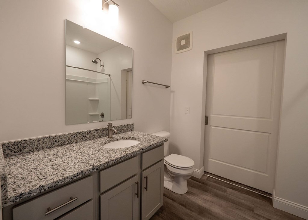 A bathroom with a granite countertop and a white sink.