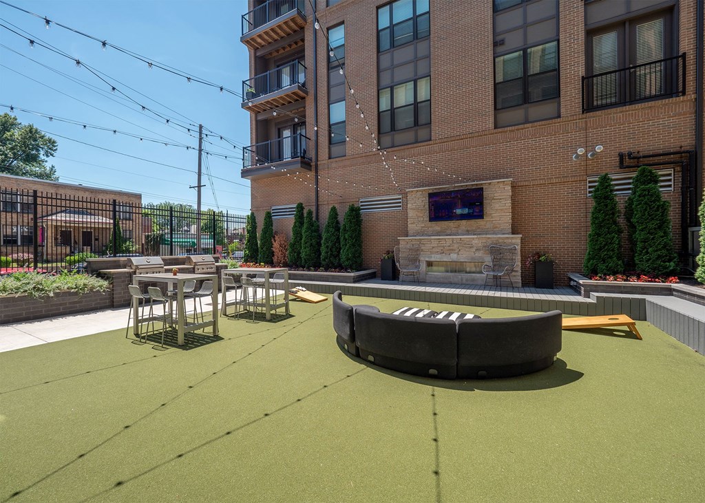 A patio area with a fire pit and seating area in front of a brick building.