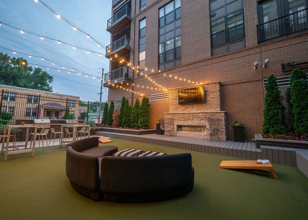 A patio with a fireplace and string lights.