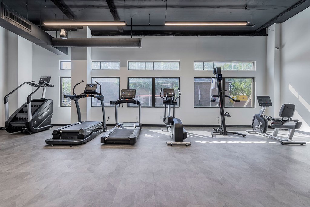 A gym with treadmills, elliptical machines, and weights.