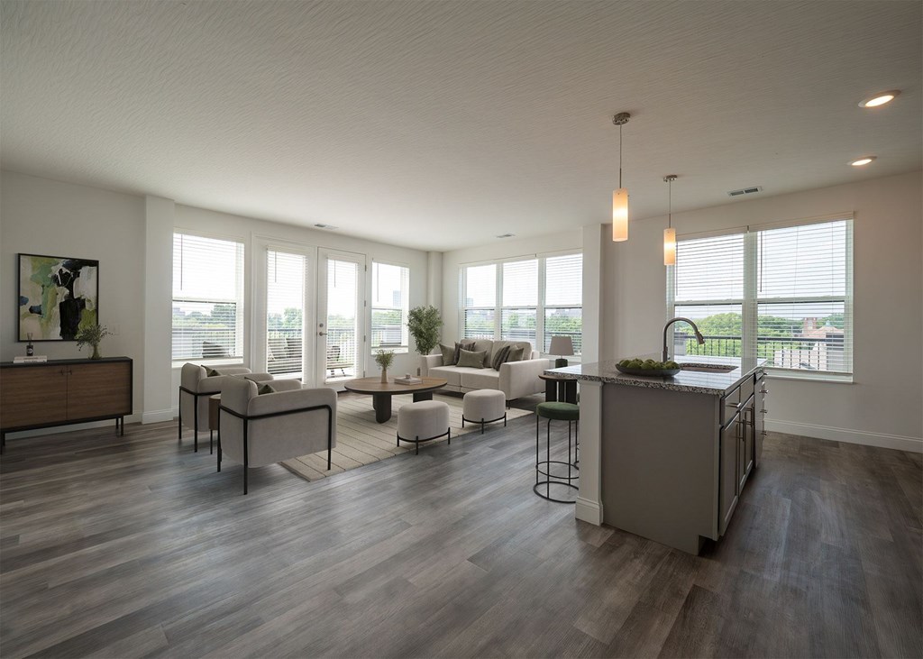 A modern living room with a kitchen area in the background.