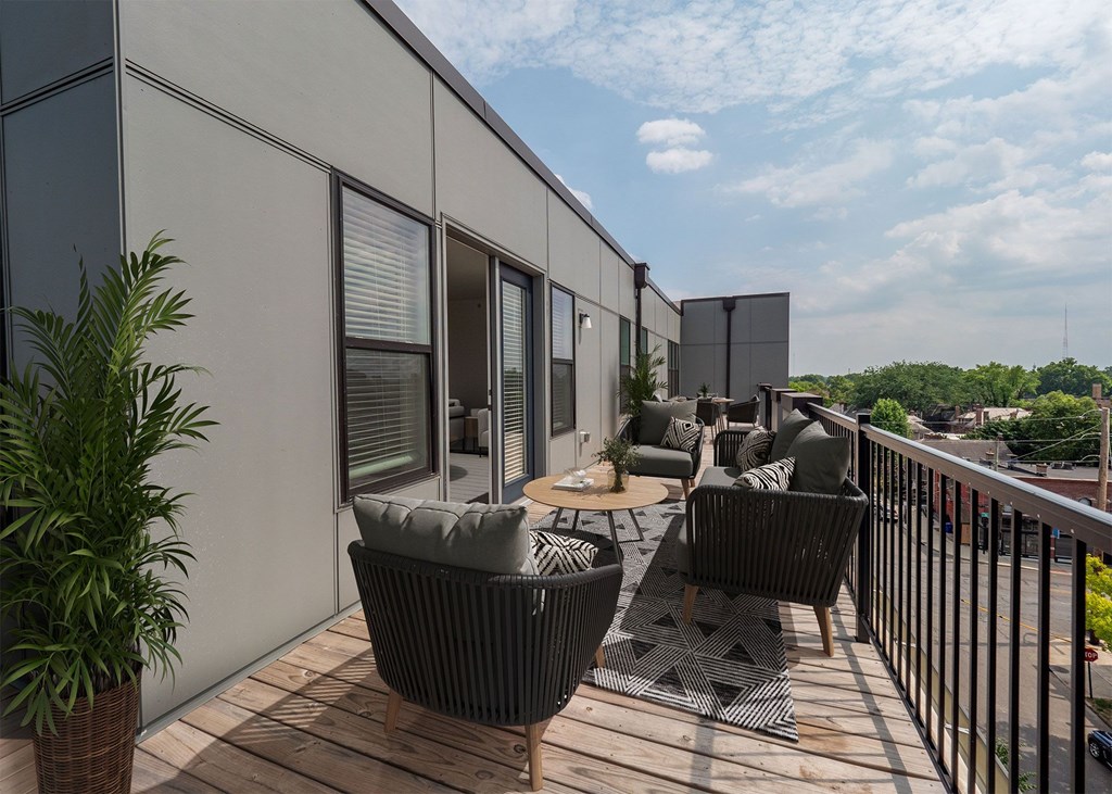 A balcony with a table and chairs overlooking a cityscape.