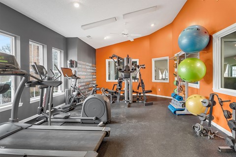 A gym with orange walls and a variety of exercise equipment.