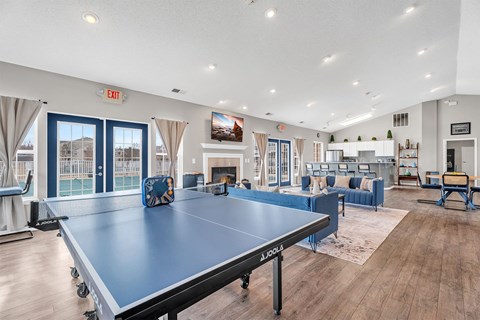 A ping pong table is in the middle of a room with a blue couch and a TV.