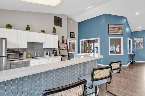 A kitchen with white cabinets and a blue backsplash.