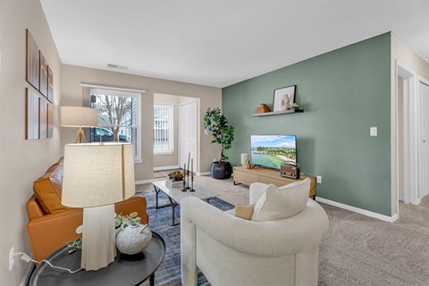 A living room with a white couch, a coffee table, a lamp, and a television.