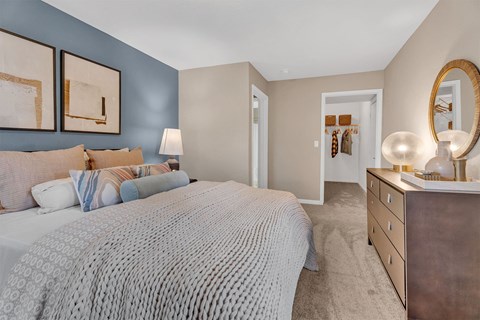 A bedroom with a bed, nightstand, and a mirror.