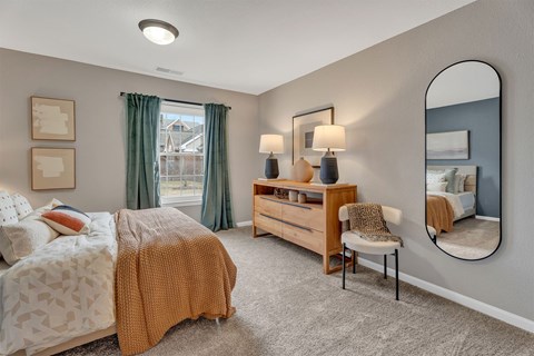 A bedroom with a bed, chair, and a mirror.