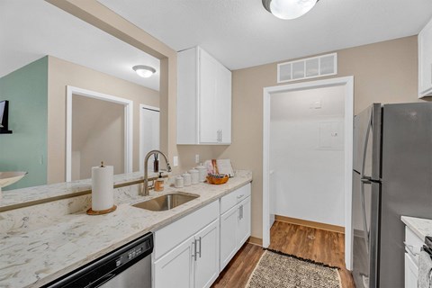 A kitchen with white cabinets and a marble countertop.