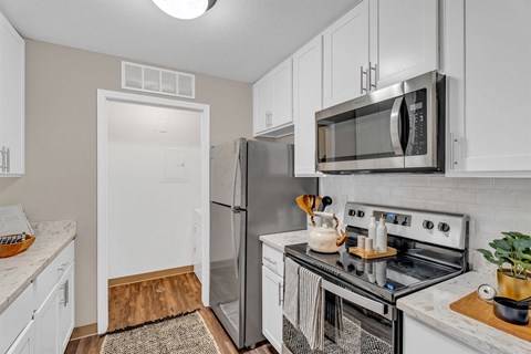 A kitchen with a stove, refrigerator, and microwave.