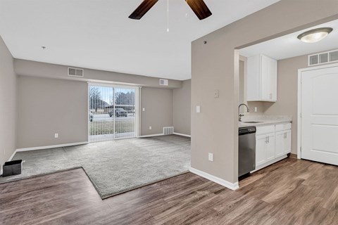 A spacious living room with a ceiling fan and sliding glass doors.