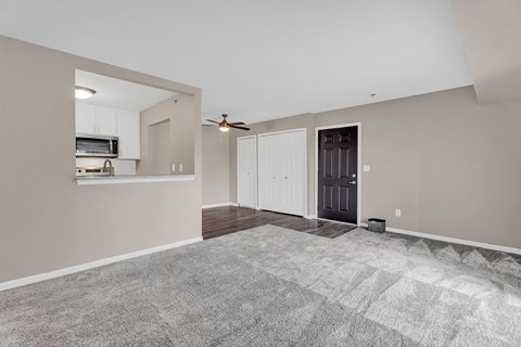 A spacious room with a ceiling fan and a door leading to another room.