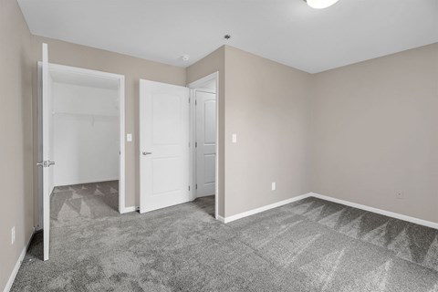 A room with a carpeted floor and two white doors.