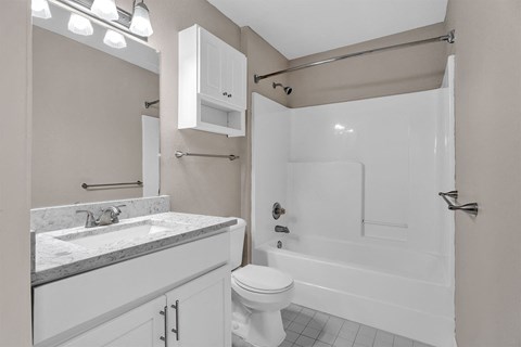 A white bathroom with a toilet, sink, and bathtub.