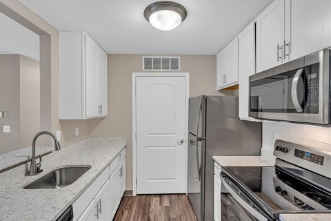 A kitchen with a white door and a stainless steel refrigerator.